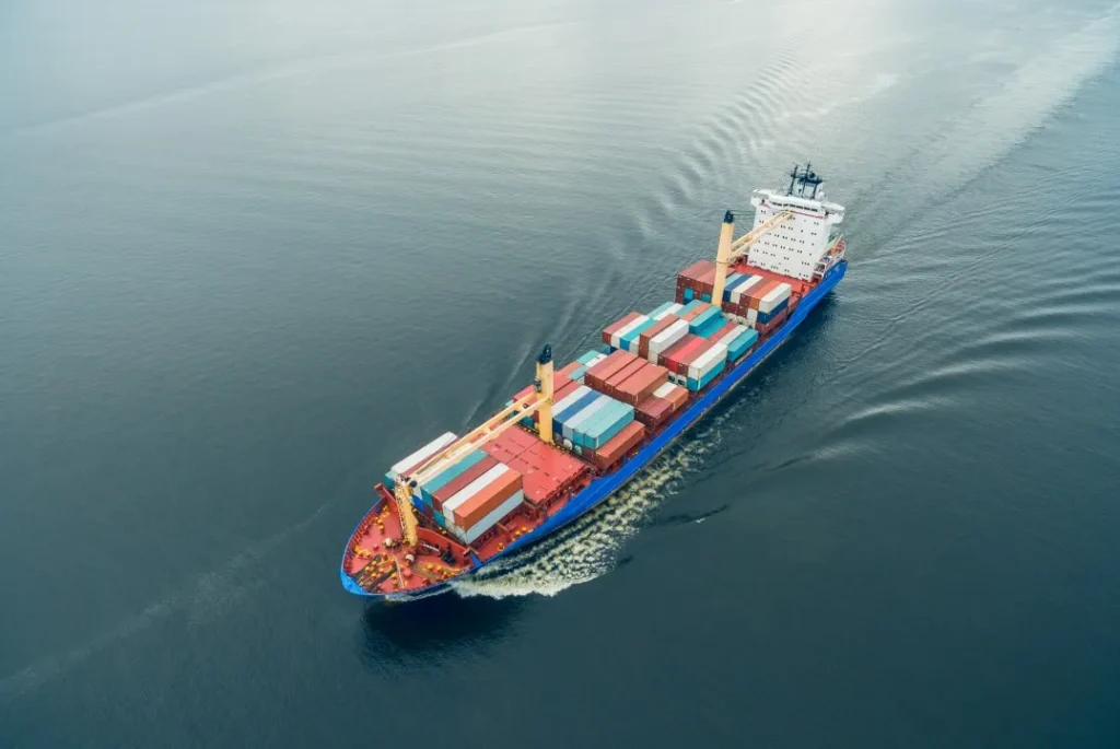 Fotografía de una toma aérea de un barco repleto de contenedores el cual está realizando un servicio de transporte marítimo en el atlántico